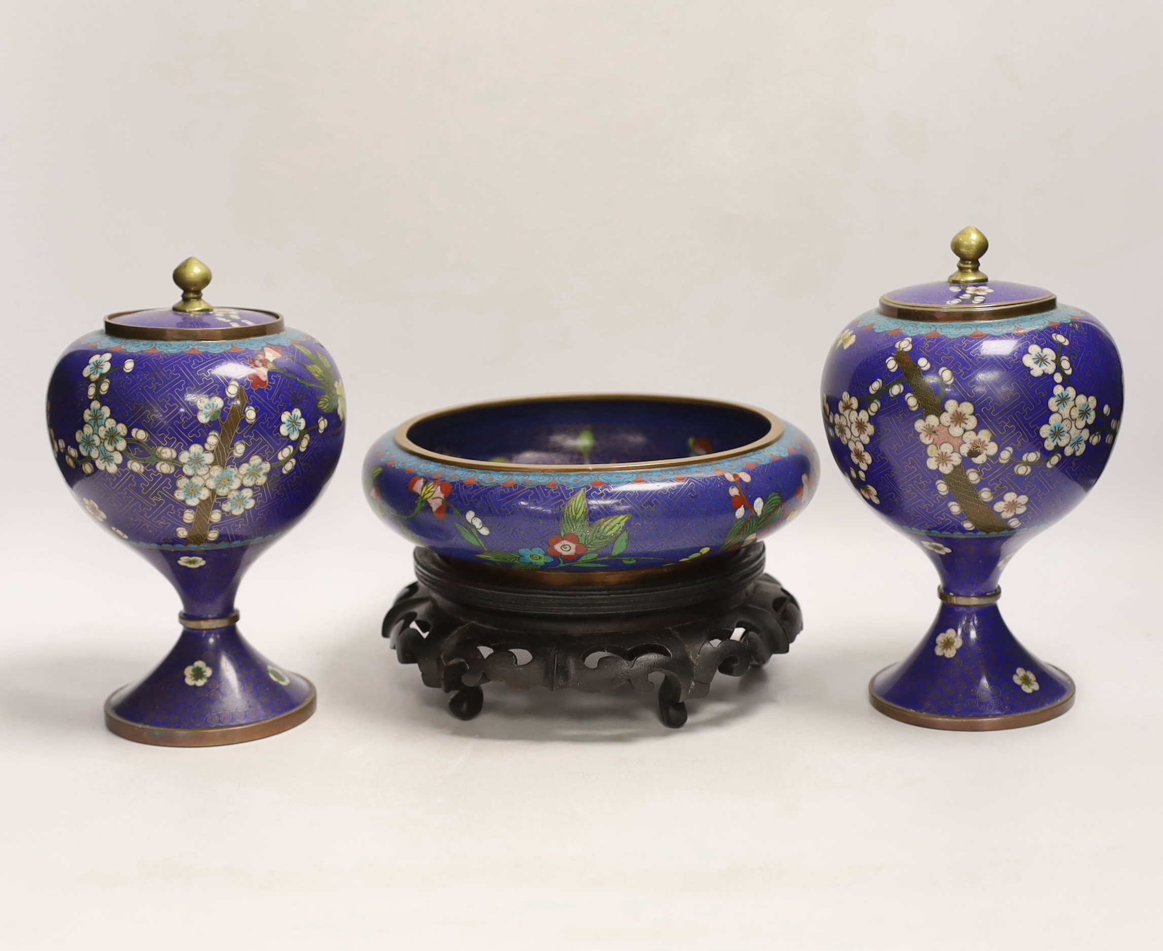 A pair of early 20th century Chinese cloisonné enamel jars and covers, together with a similar bowl and wood stand, largest 20cm high